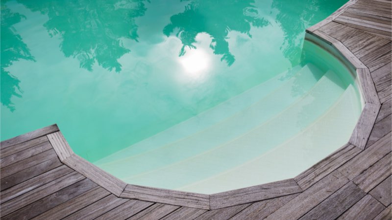 Pool mit trübem Wasser und Holzdeck im Außenbereich