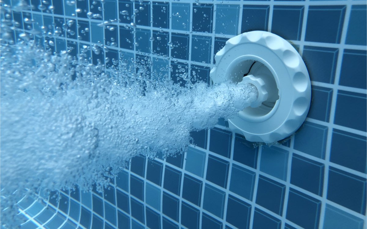Pool-Einlaufdüse in der Beckenwand mit austretendem Wasser