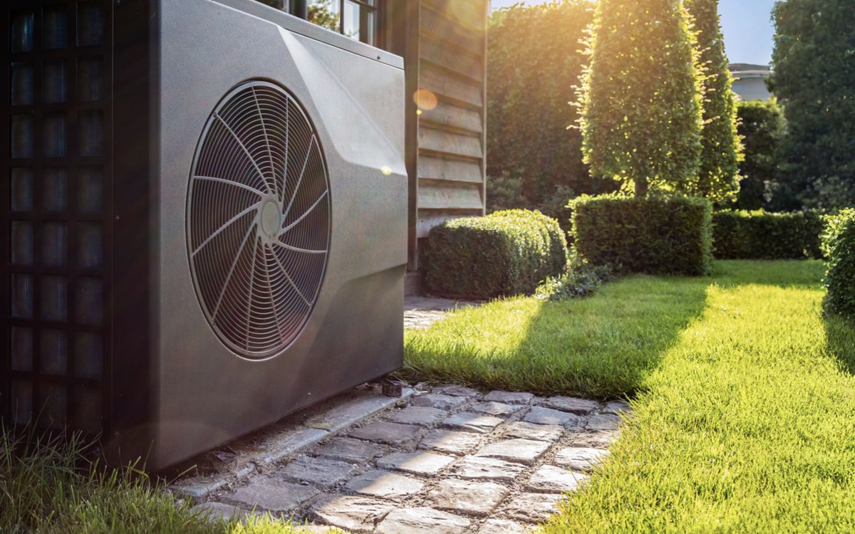 Wärmepumpe im Garten neben einem Wohnhaus