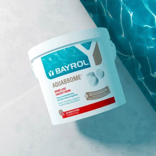 BAYROL Aquabrome – Produkt am Poolrand mit blauem Wasser im Hintergrund