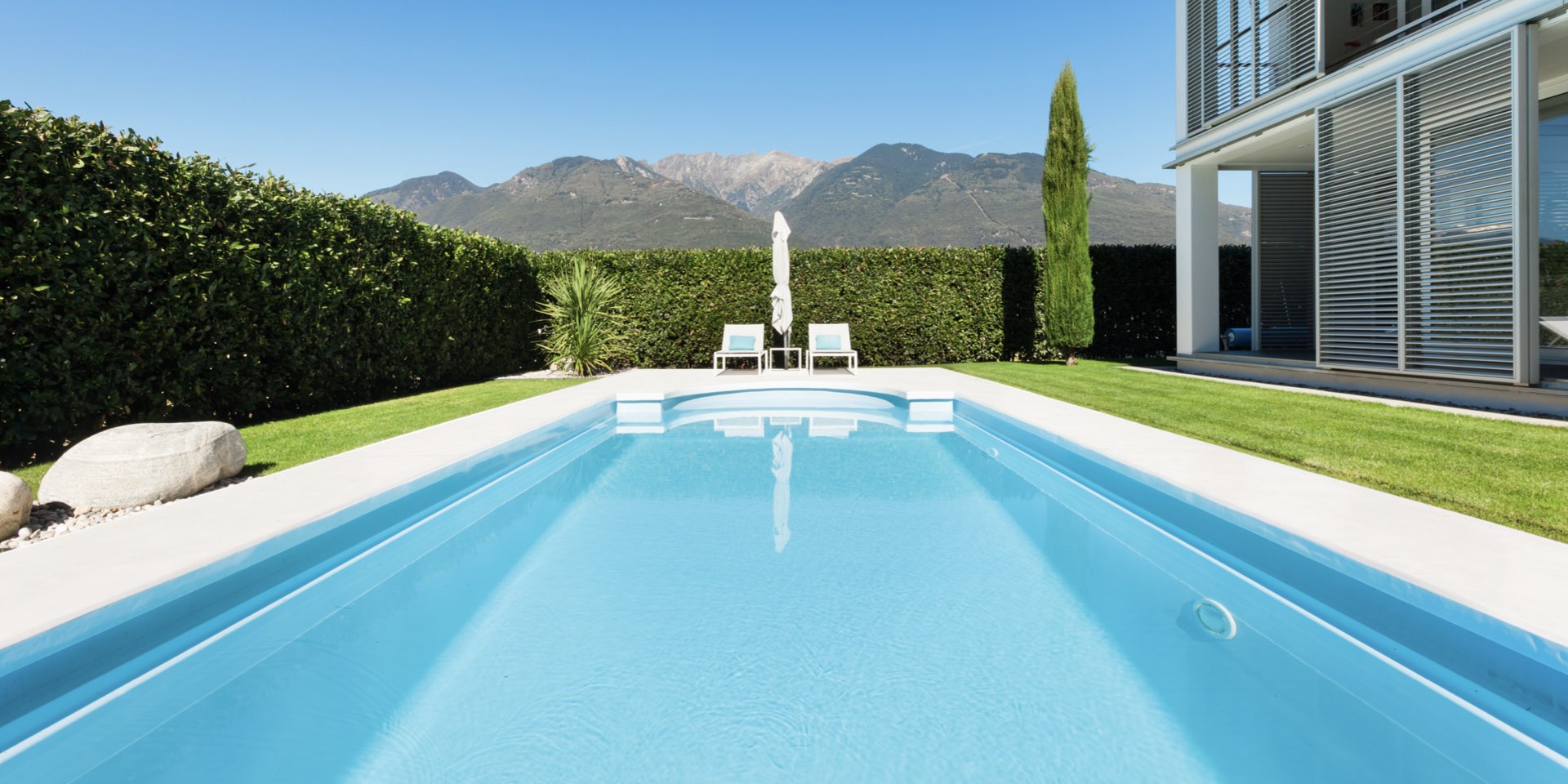 Luxuriöser Außenpool mit moderner Villa, gepflegtem Garten und Bergpanorama
