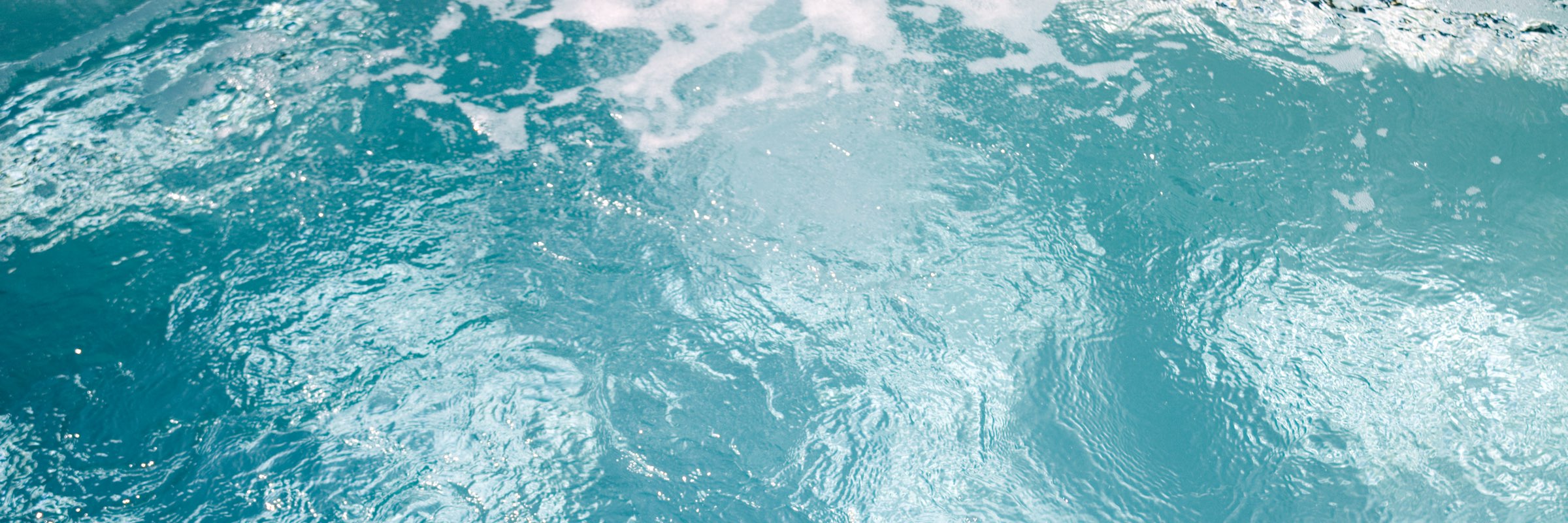 Milchig-trübes Poolwasser mit Schlieren auf der türkisfarbenen Wasseroberfläche